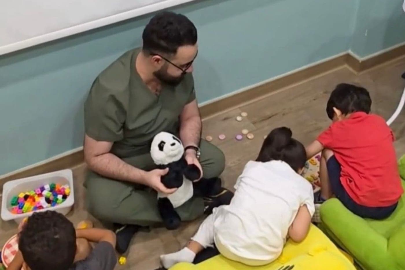 أخصائي تعديل السلوك يجلس مع مجموعة من الأطفال على الأرض في نشاط جماعي داخل مركز الفارس الصغير